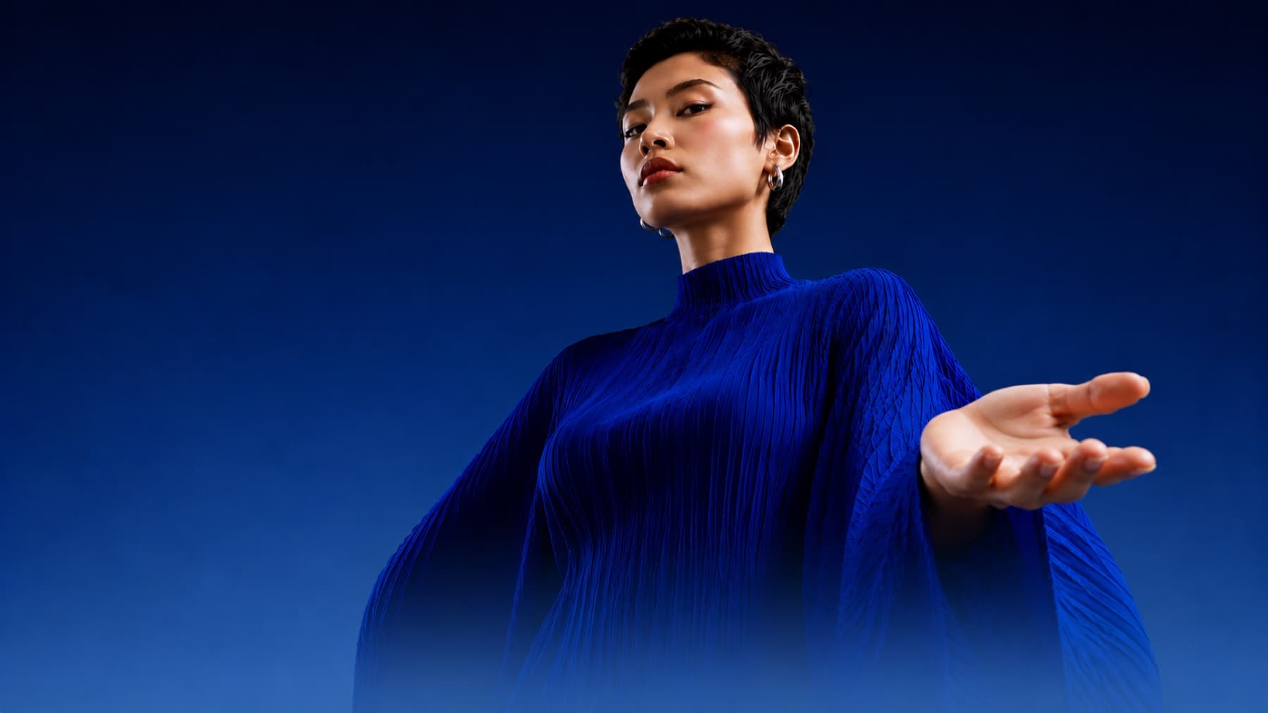 A woman in deep blue with an open, upturned palm